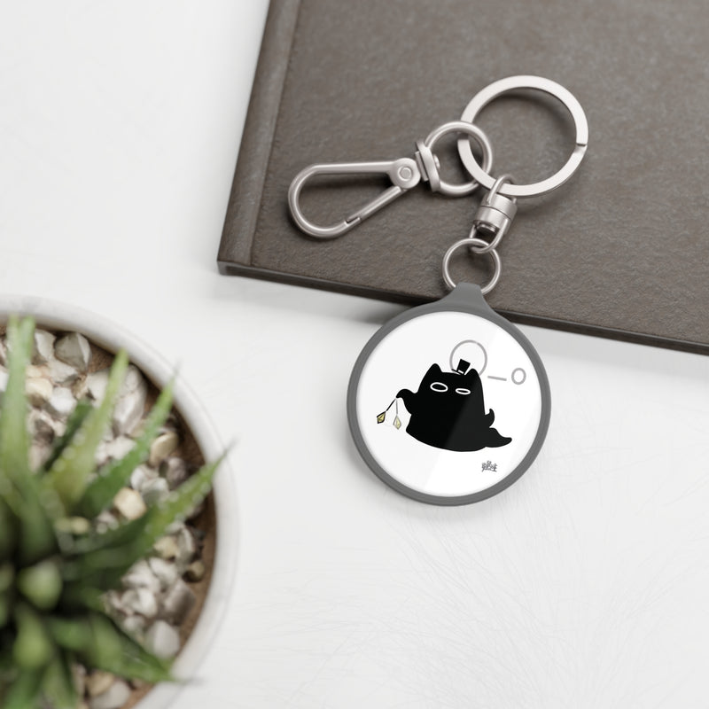 Lord of the Mysteries Cat Keyring - Lifestyle photo with succulent plant and dark book, showing scale