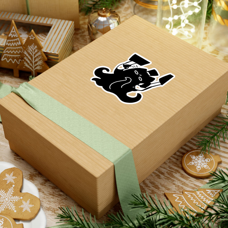 Eldritch Chef Meow sticker on gift box with festive holiday decorations, gingerbread cookies and green ribbon - LOTM merch lifestyle photo