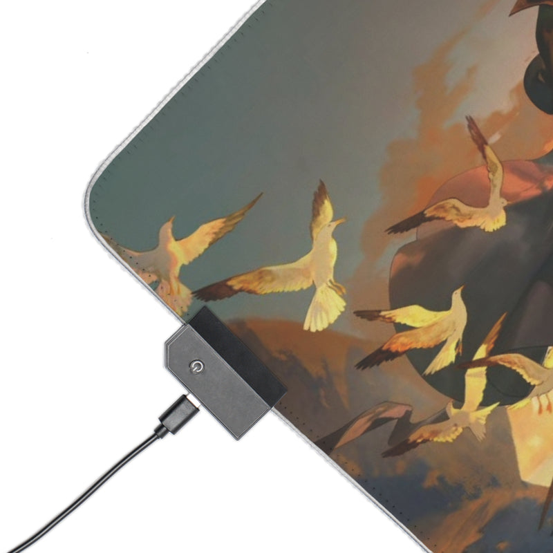 Close-up detail of RGB mouse pad corner showing golden birds artwork, USB-C power button and stitched edge binding